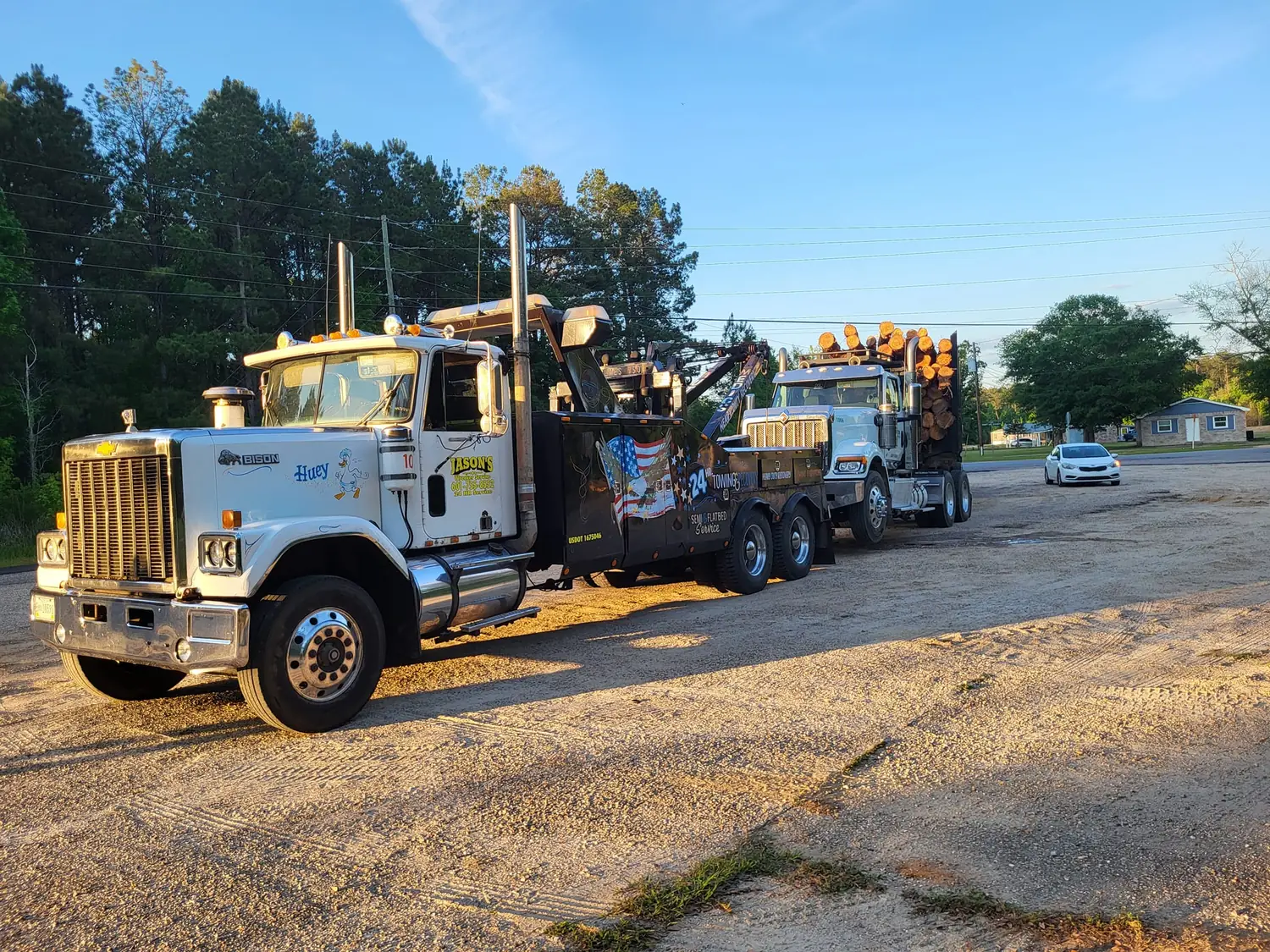 Jason's Wrecker Service's heavy wrecker "Huey" towing a fully loaded log truck on a Wayne County road at sunset