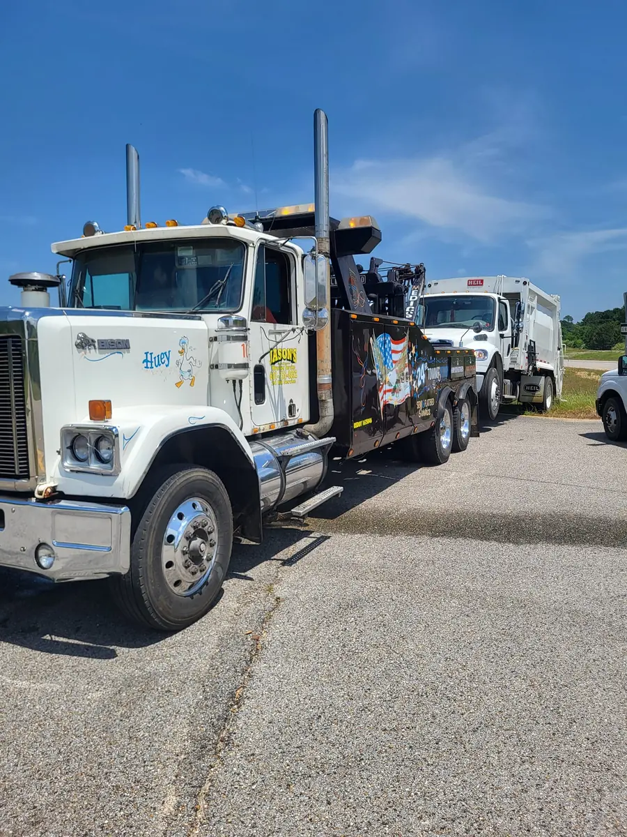 Jason's Wrecker Service's heavy wrecker hooked to a rear-loader refuse truck, showing the flag and eagle door graphic