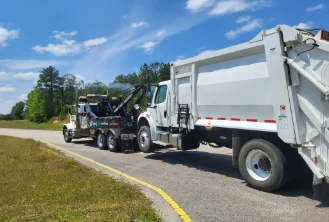 Jason's Wrecker Service's heavy wrecker towing a refuse truck along the roadside